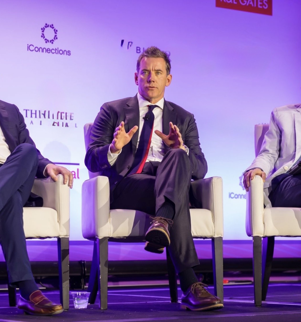 Daniel Leger speaking while seated on a panel at an investor conference